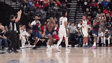 a group of basketball players are standing on a court and one of them has the number 5 on his shirt .