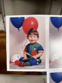 a baby is holding a red balloon and a blue balloon with the number 1 on it