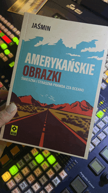 a book titled amerykańskie obrazki is being held in front of a keyboard