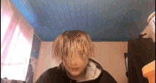 a person with blonde hair is standing in a room with blue ceilings