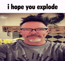 a man with glasses and a beard is wearing a grey shirt that says i hope you explode