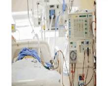 a person is laying in a hospital bed with a dialysis machine in the background .