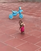 a little girl is walking on a tiled floor .