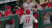 a group of baseball players are standing in a dugout . one of the players is wearing a number 17 jersey .