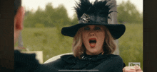 a woman wearing a black hat with feathers is screaming at a man