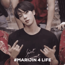 a young man wearing a saint laurent t-shirt is making a peace sign