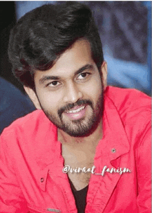 a man with a beard wearing a red jacket is smiling for the camera .