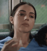 a woman in a blue shirt is sitting on a couch and looking at the camera