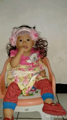 a little girl wearing a pink headband is sitting on a chair with the date 2021/2/13 at the bottom