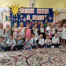 a group of children are posing for a picture in front of a sign that says dzien mamy i taty