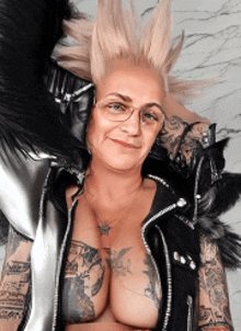 a woman with a mohawk and glasses is wearing a black vest