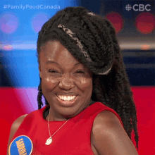 a woman with braids is smiling and wearing a red shirt with a badge that says jamaica on it .