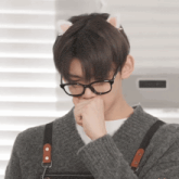 a young man wearing glasses and cat ears covering his mouth with his hand