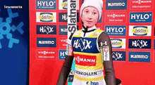 a person standing in front of a wall that has a lot of logos on it including hylo