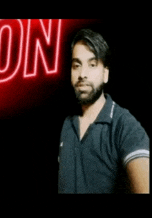 a man with a beard and mustache is standing in front of a neon sign that says on .