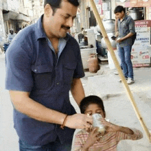 a man is giving a can of soda to a young boy .