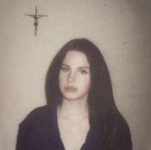 a woman in a black shirt is standing in front of a cross on a wall .