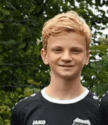 a young man wearing a jako jersey is smiling for the camera