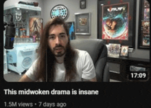 a man with long hair is sitting in front of a microphone with the time of 17:09