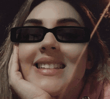 a close up of a woman wearing sunglasses with her hand on her face