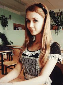 a girl with a bow in her hair is sitting at a desk in a classroom