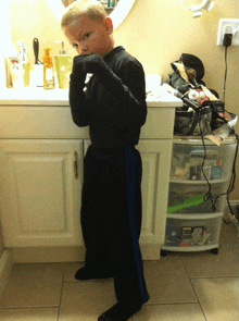 a young boy stands in front of a bathroom counter with a container of shaving cream on it