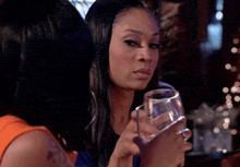 a woman is holding a glass of wine and looking at the camera .