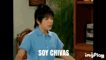 a boy in a blue shirt says soy chivas in a living room