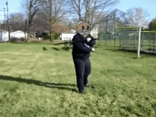 a man with a cartoon character on his head is holding a baseball bat in a field