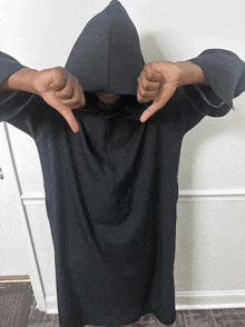 a person wearing a black hoodie giving a thumbs down