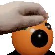 a person is putting a towel on top of an orange ball with a black eye .