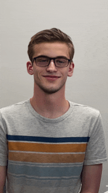 a young man wearing glasses and a striped shirt smiles at the camera