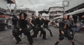 a group of men are dancing on a street in front of a building that says ' tesco ' on it