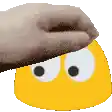 a hand is covering a yellow smiley face with a slipper .