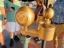 a group of people standing around a gold mickey mouse sign