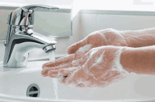 a person is washing their hands in a sink with soap