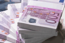 a stack of 500 euro bills sits on top of a stack of 100 euro bills