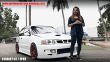 a woman stands in front of a white car that says starlet gt