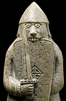 a stone statue of a man with a beard and a helmet holding a sword and shield .