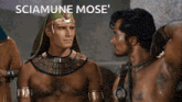 a man without a shirt is standing next to another man with the words sciamune mose ' written above him
