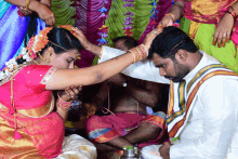 a bride and groom are sitting on the floor and the bride is putting something on the groom 's head