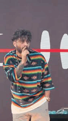 a man with a beard is singing into a microphone while wearing a colorful shirt .