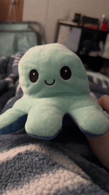 a person is holding a stuffed octopus that has a smile on its face