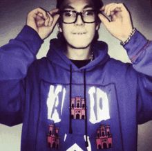 a man wearing glasses and a purple hoodie with the letter k on the front