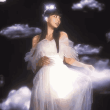 a woman in a white dress and tiara stands in front of a cloudy sky