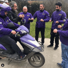 a group of men in purple getir jackets are standing around a purple scooter