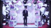 a man in a suit and top hat is standing in front of a wall of televisions
