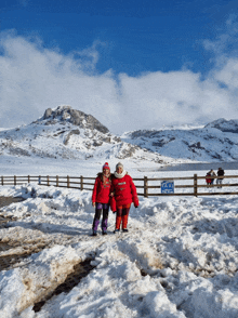 two people standing in the snow with a taxi sign behind them