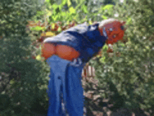 a scarecrow with pumpkins in his butt is standing in the woods