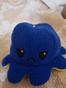 a blue stuffed octopus has a sad face on it